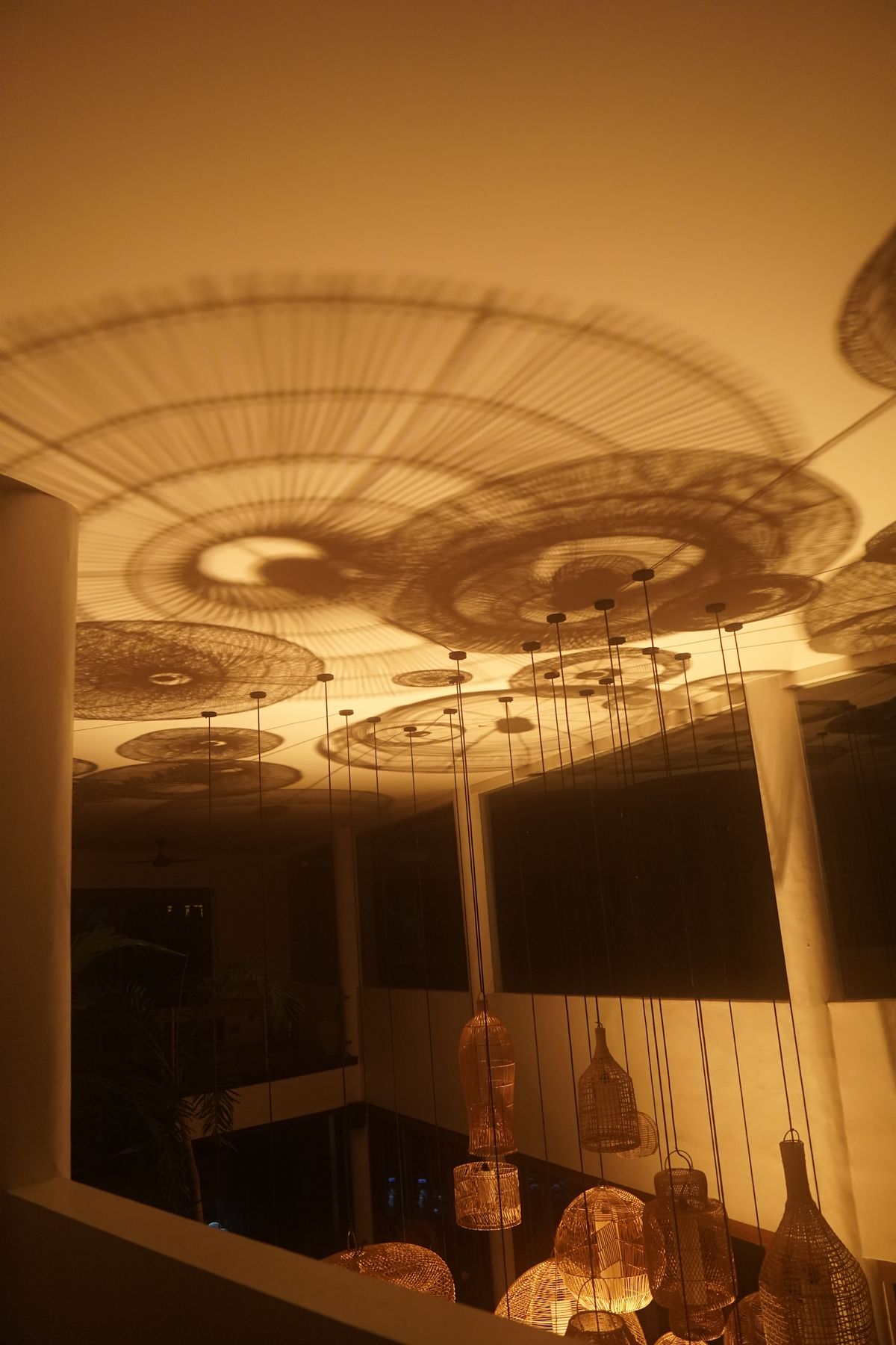 Ceiling shadow patterns cast by AVA Light through rattan pendants, the ceiling-bounce effect in action